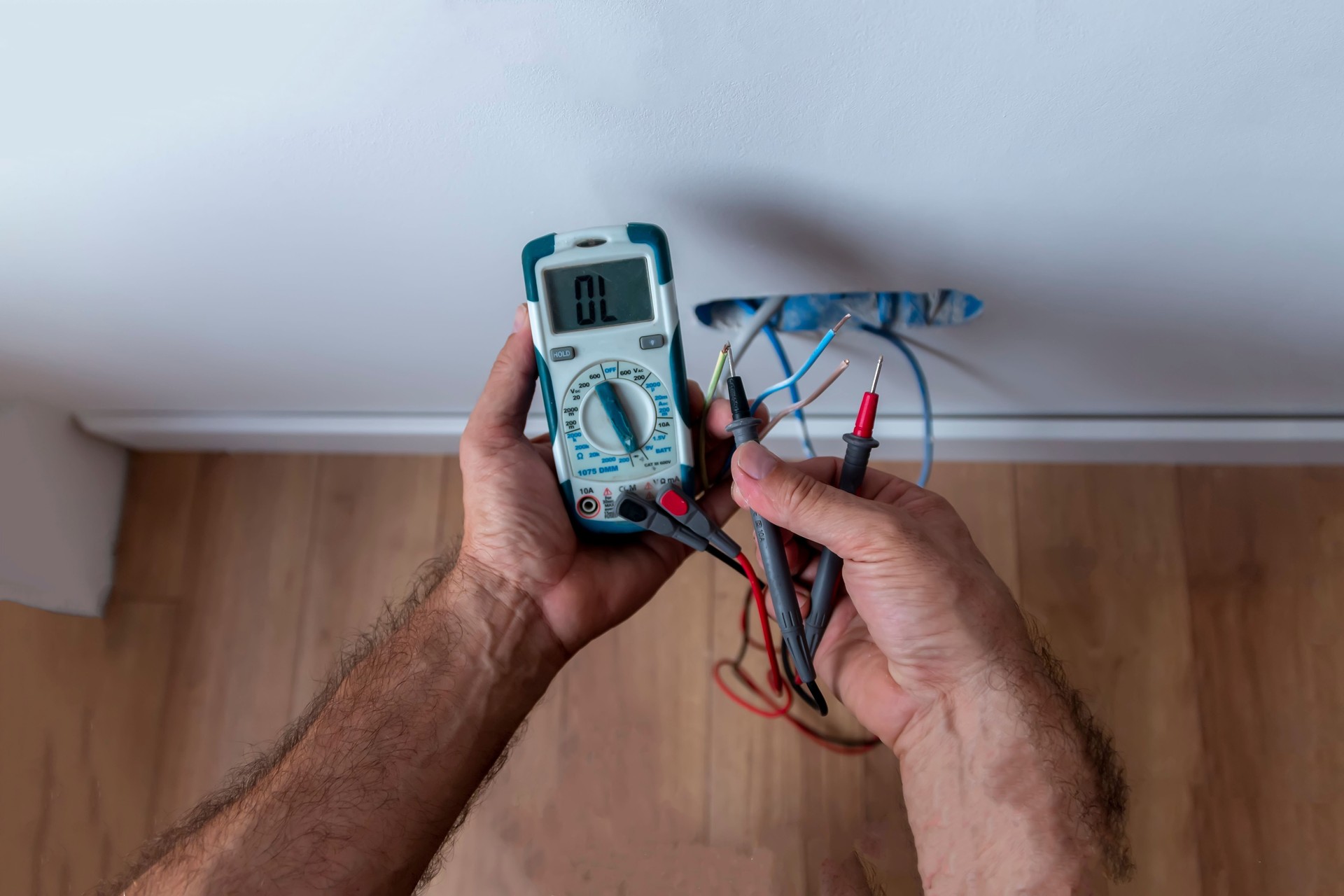 Electrician is using a digital meter to measure the voltage at the power outlet